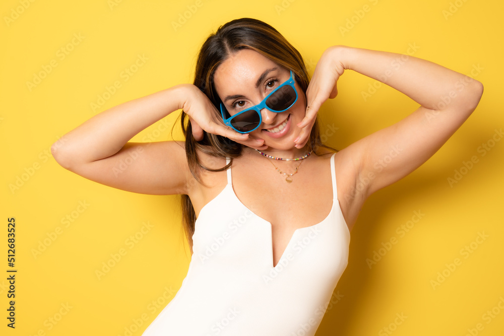 Naklejka premium Portrait of smiling brunette young woman with sunglasses isolated over yellow background.