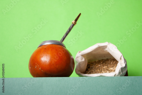 yerba and mate leaves in a paper bag on a green podium, selective focus photo