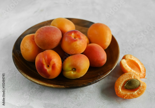 Fresh ripe apricots in a wooden bowl on a table made of natural marble.  Apricots are rich in vitamins and minerals, such as: vitamin A, beta-carotene, vitamin C, potassium, silicon, cobalt