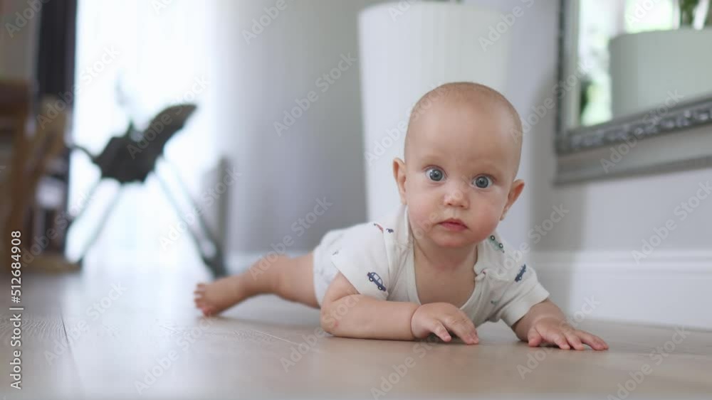 crawling infant baby, lying on floor indoors, learning crawl towards camera, show emotions, crying, smiling, looking camera. curious baby, exploring world around room home. first moves stomach belly crawling infant baby, lying on floor indoors, learning crawl towards camera, show emotions, crying, smiling, looking camera. curious baby, exploring world around room home. first moves stomach belly