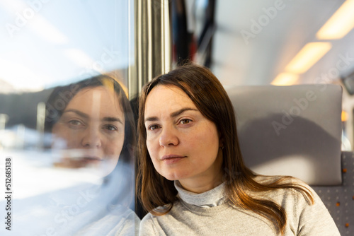 Closeup portrait of contemplative brunette woman travelling by express train, sitting on soft comfortable seat and looking out window