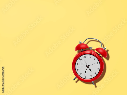 Alarm clock. Top view photo. Classic red metal alarm on yellow desk.