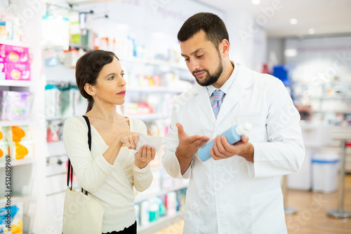 Female buyer consults the pharmacist which lotion or ointment to buy at the pharmacy