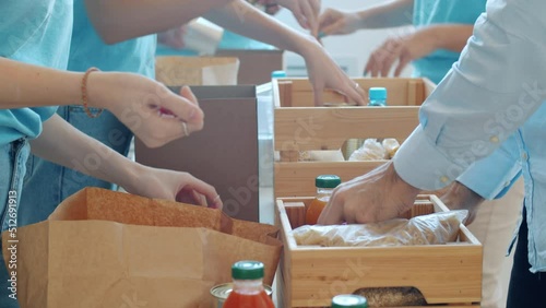 Close-up of hands putting groceries in containers collecting donation for charity in busy office. Teamwork and helping poor concept.