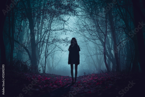Girl on the road in a mysterious forest. Background wallpaper. Strange forest. Mystic atmosphere. Dark scary road. Paranormal another world. Ghost in the fog. The pursuit. Horrible dream.