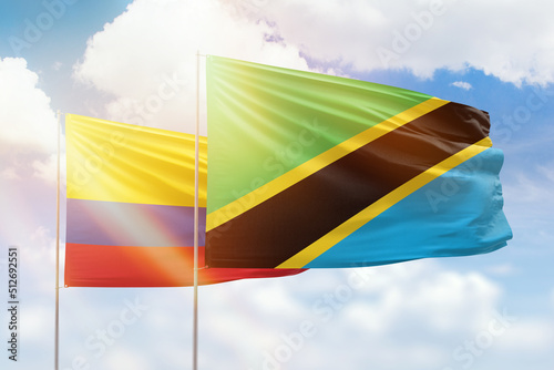 Sunny blue sky and flags of tanzania and colombia