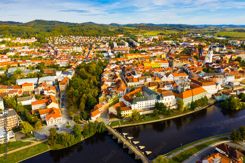 Autumn landscape with Old Town of Czech city of Pisek on banks of Otava river on sunny day..