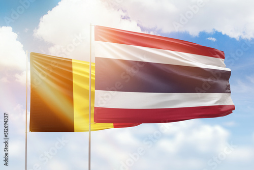 Sunny blue sky and flags of thailand and belgium
