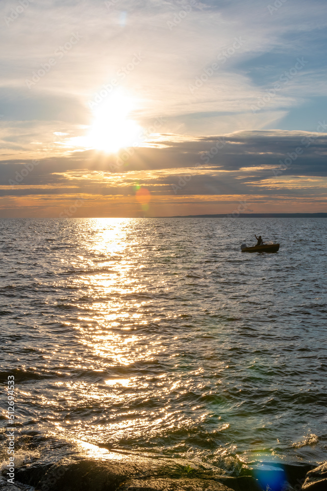 A lone boat floats on Lake Nippising as its rider enjoys the beautifully colour sunset in North Bay, Ontario. A lone boat floats on Lake Nippising as its rider enjoys the beautifully colour sunset in North Bay, Ontario.