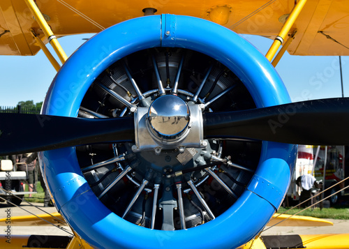 A closeup of an engine, prop and cowling of a biplane on display at an airshow.