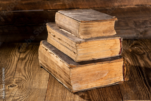Old worn books on a textured wooden table.