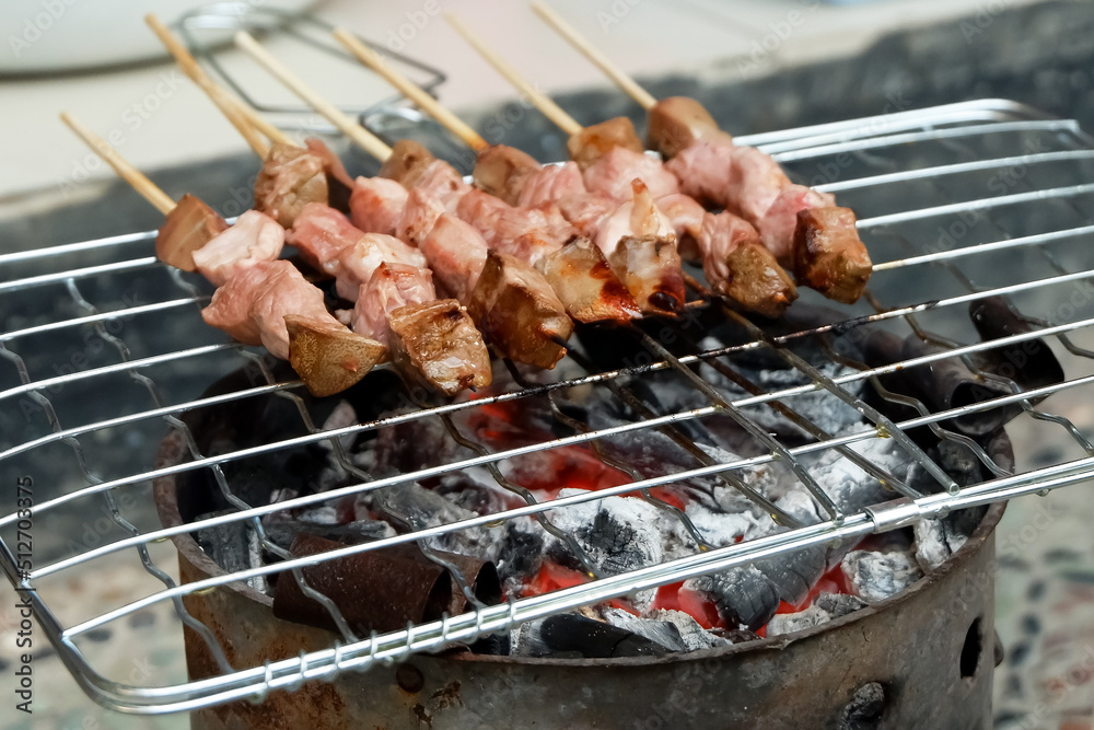 Sate Sapi or meat satay, the process of making satay on a charcoal grill.
