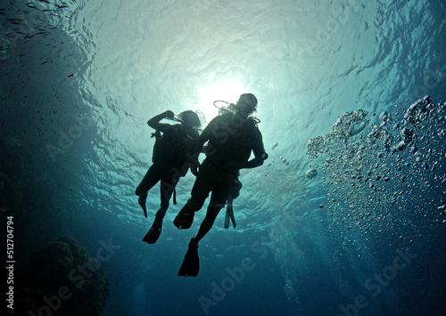 Two scuba divers close to ocean surface looking down in silhouette withe sun behind them - Sail Rock Island in southern Thailand