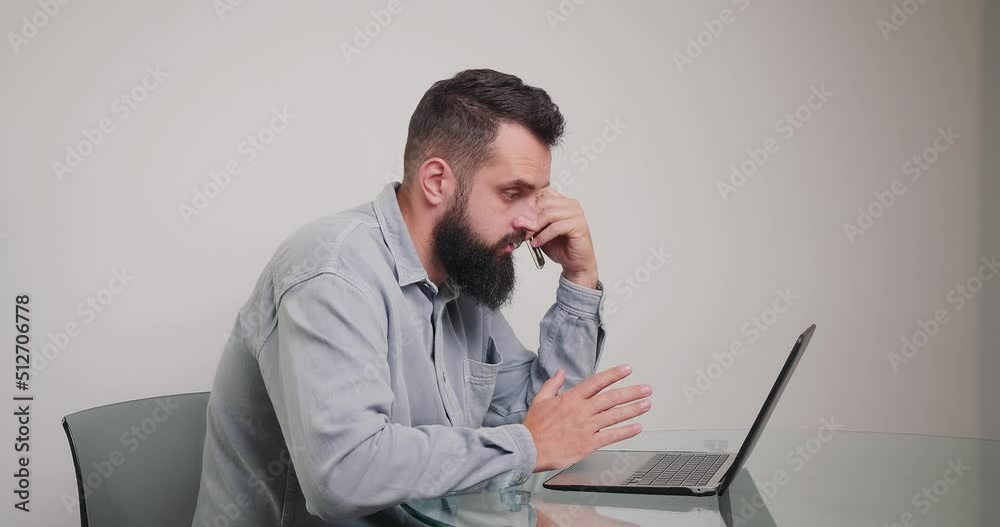 Busy bearded man works on laptop distracting on phone call and closes laptop. Busy bearded man works on laptop distracting on phone call and closes laptop.