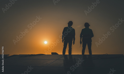 Engineers walking on roof inspect and check solar cell panel by hold equipment box and radio communication ,solar cell is smart grid ecology energy sunlight alternative power factory concept.