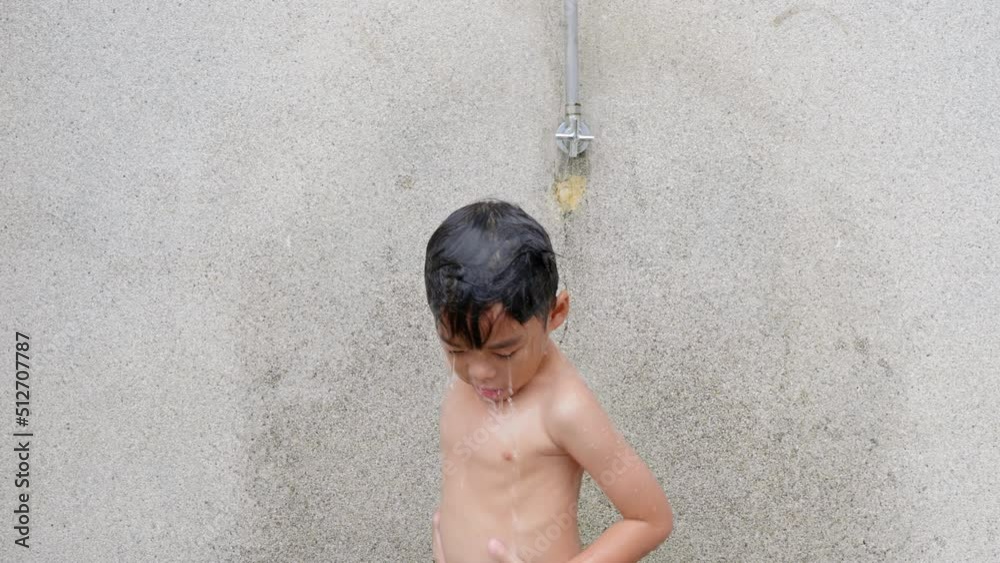 Asian child little boy taking shower at the swimming pool resort, Happy
