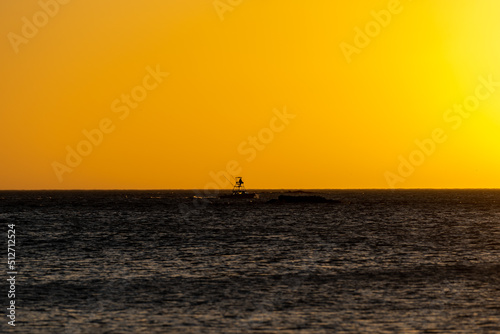 Beautiful view of an orange sunset in the midel of the Costa Rica Ocean, with a boat and pelicans  photo