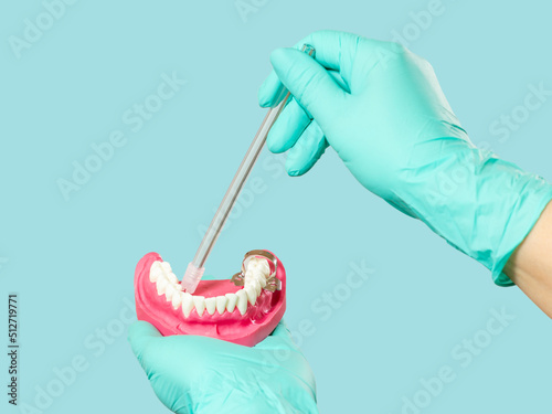 Dentist's hands in gloves with saliva ejector and human jaw layout.