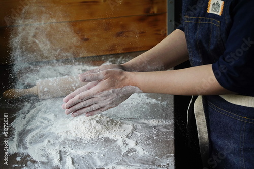 The woman slaps her hands in flour over the table.