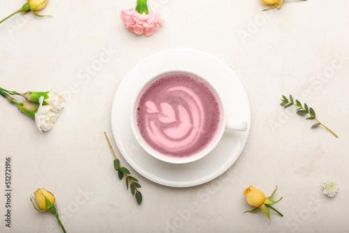Cup of pink matcha tea with beautiful spring flowers on light background