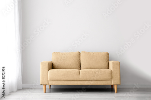 Comfortable beige sofa near light wall