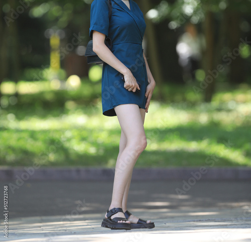 beautiful legs of a girl in a blue skirt in the park