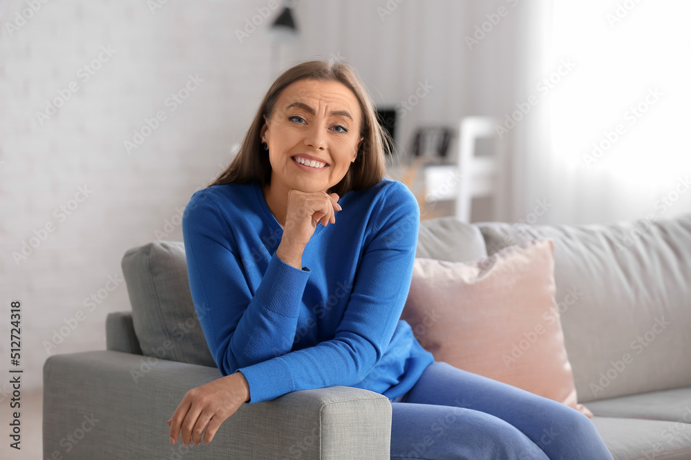Happy senior woman sitting on sofa at home. Process of aging