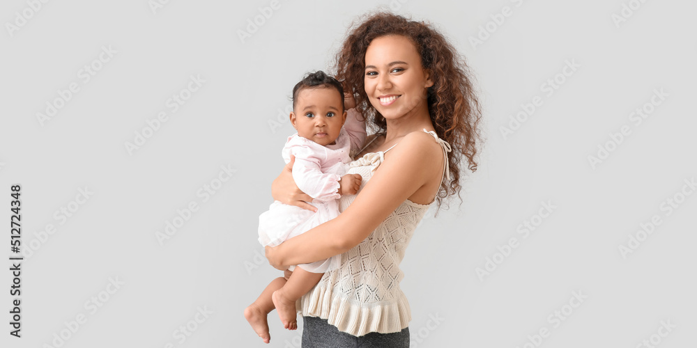 African-American woman with cute little baby on light background African-American woman with cute little baby on light background