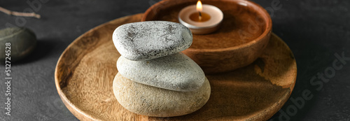 Canvas Print Wooden tray with stack of stones and candle on dark background