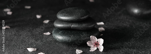 Canvas Print Stack of spa stones and flowers on dark background. Zen concept