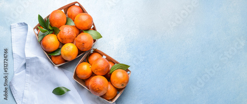 Boxes with fresh blood oranges on light blue background with space for text, top view