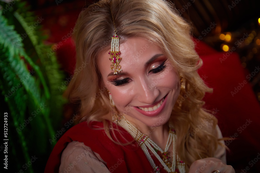 A beautiful European girl looking like an Arab woman in a red room in a harem. Photo shoot of an oriental style odalisque. A model poses in a sari as an indian woman in india A beautiful European girl looking like an Arab woman in a red room in a harem. Photo shoot of an oriental style odalisque. A model poses in a sari as an indian woman in india
