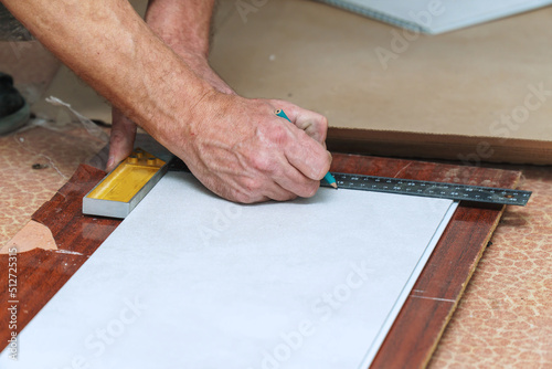The worker marks the plastic panel with a pencil and tape measure or ruler. Selective focus