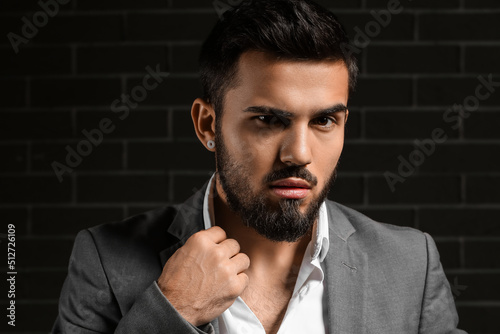 Bearded businessman adjusting collar on dark background Fototapet