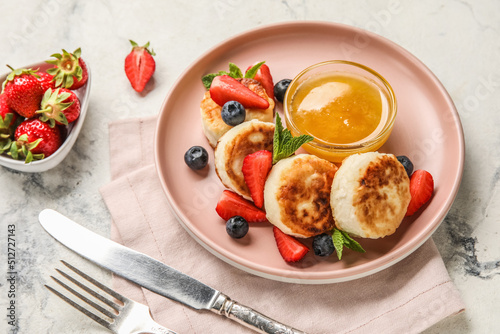 Plate with delicious cottage cheese pancakes, berries and honey served on light background