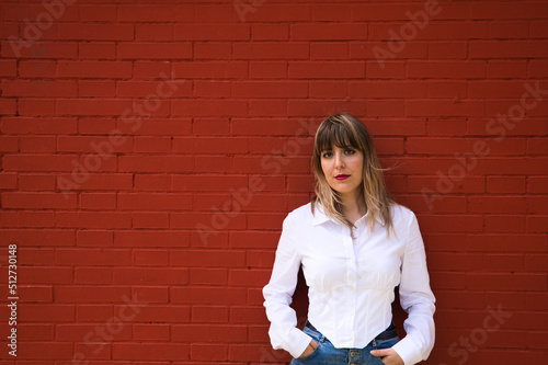 Pretty, blonde, young woman having fun making different expressions in front of a red background wall. Concept various expressions. Laughter, sadness, tired, angry, hate.