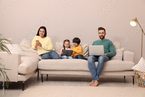 Happy family with gadgets on sofa in living room