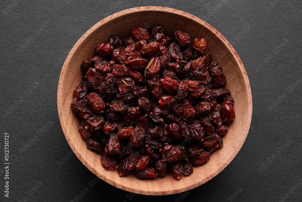 Dried barberries in wooden bowl on grey background, top view Dried barberries in wooden bowl on grey background, top view