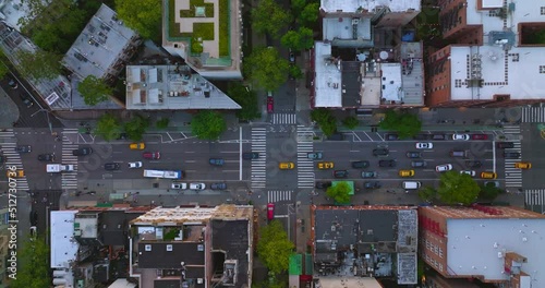 Lots of yellow taxi cabs moving among other transport by the streets of New York. Buildings tops from aerial view.