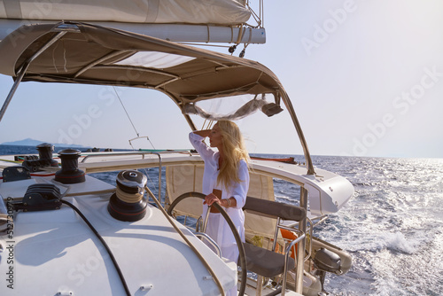 beautiful woman standing on yacht captain's bridge at sunny summer day