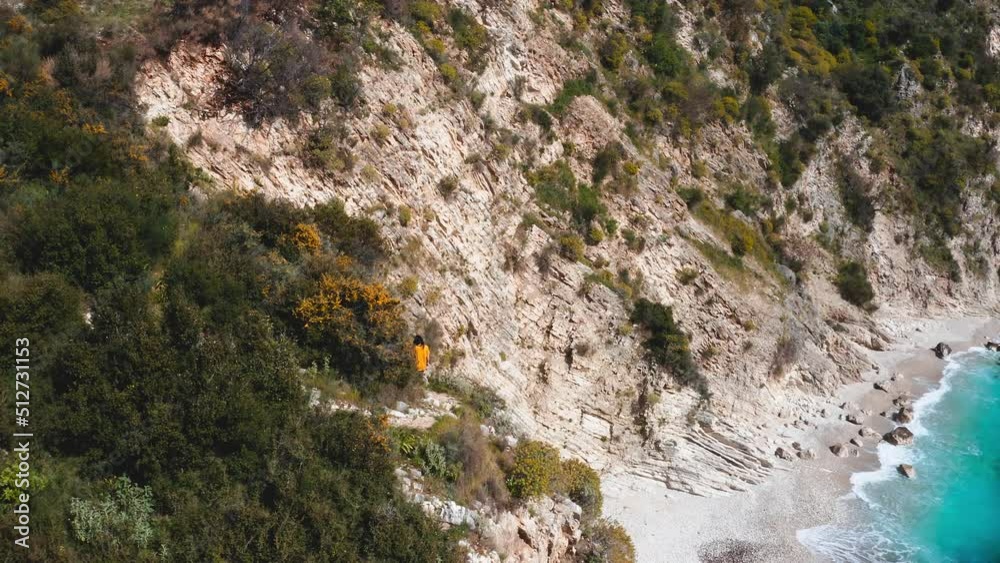 Fearless woman walking along edge of a cliff above blue turquoise water beach Fearless woman walking along edge of a cliff above blue turquoise water beach
