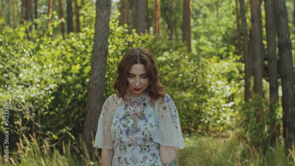 attractive woman with red lips touches her curly hair walk in the forest slow motion. blue sea with waves and blue sky in the background. attractive woman with red lips touches her curly hair walk in the forest slow motion. blue sea with waves and blue sky in the background.
