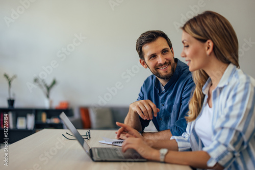 Businessman and businesswoman working together online, using a laptop.
