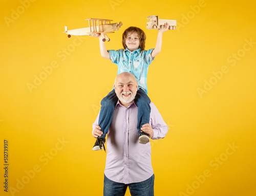 фотографія Child boy and grandfather playing piggyback ride with plane and wooden toy truck