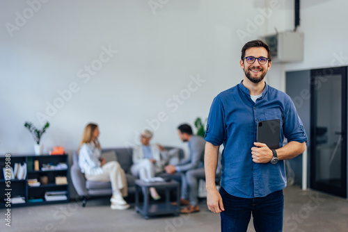 Portrait of an adult company employer, holding a tablet, posing for the photo.