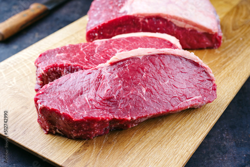 Raw dry aged wagyu roast beef steak offered as close-up on a wooden design board