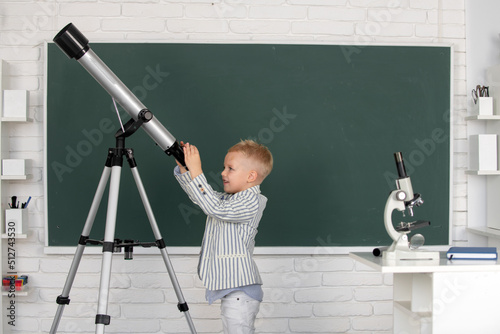 Foto Cute little child with telescope in classroom at elementary school