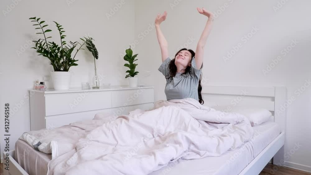 Beautiful woman wakes up and stretching in bed. Beautiful bright room in a modern style Beautiful woman wakes up and stretching in bed. Beautiful bright room in a modern style