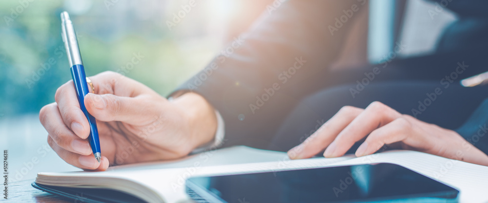 Woman hand writing on a notepad with a pen in the office.
