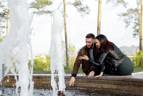 Beautiful couple in love on romantic dating in summer city park, sensual relationship of young man and woman having fun at fountain, candid lifestyle